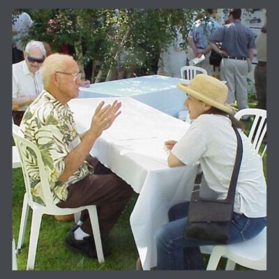Elderly-man-talking-to-younger-woman-at-bungalow-neighborhood-historic-preservation-event